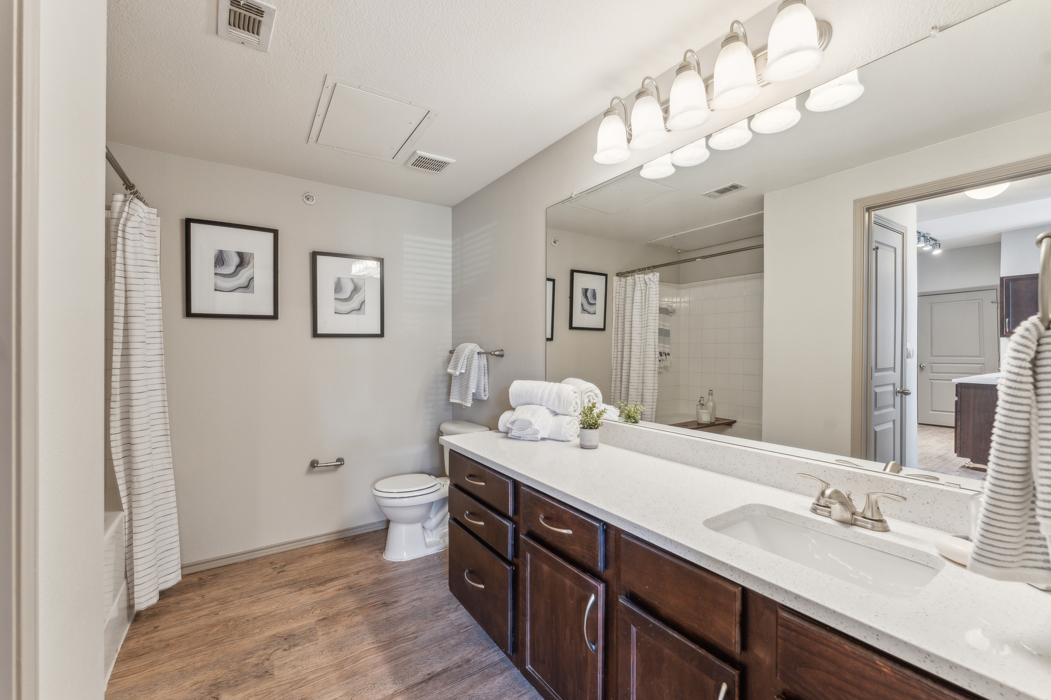 a bathroom with a large mirror and wood cabinets at The  Wyatt at Presidio Junction